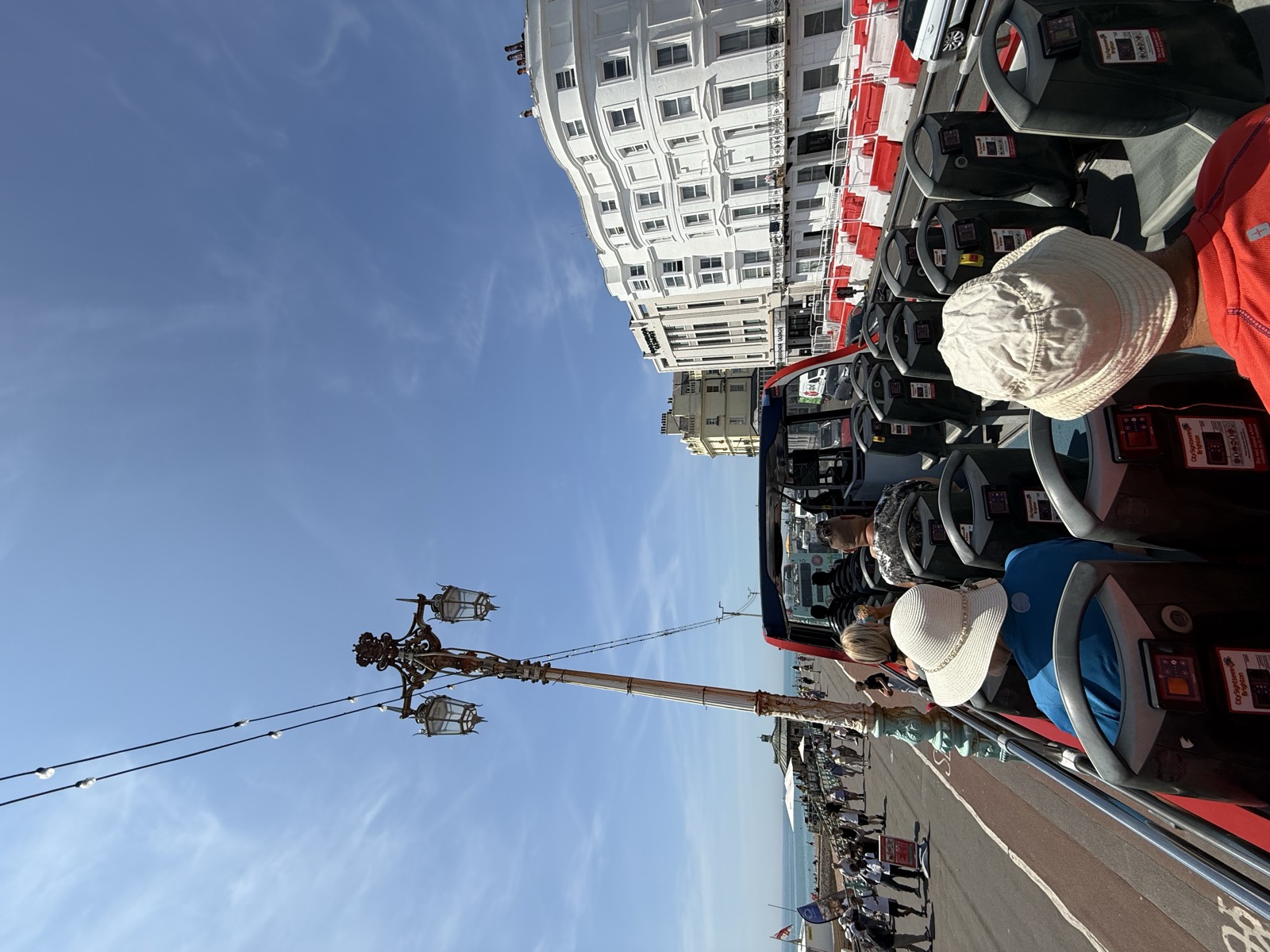 View from the open top deck of the City Sightseeing Brighton hop-on hop-off bus along the seafront, passengers in sun hats